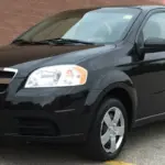Black four-door Chevrolet sedan parked in a lot, front-left angle, with dealership plate reading RIDE TIME on the bumper portion plate frame