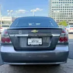 Rear view of a gray Chevrolet Aveo LT in a dealership lot with a Panda Autos plate frame.