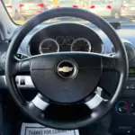 Close-up of a Chevrolet steering wheel with the instrument cluster in the background, parked in a lot.